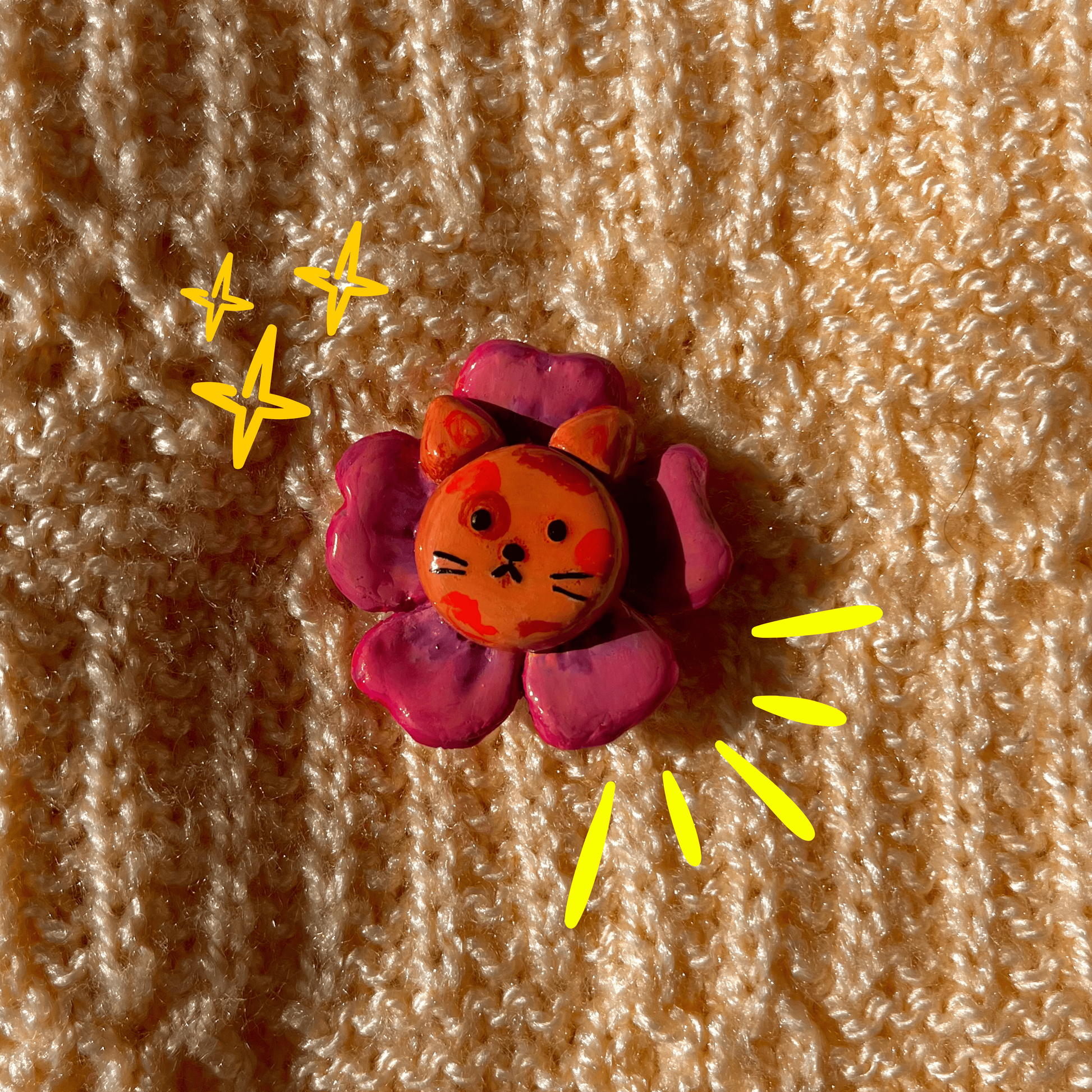 Flower-shaped object with a cat face design on a textured brown background
